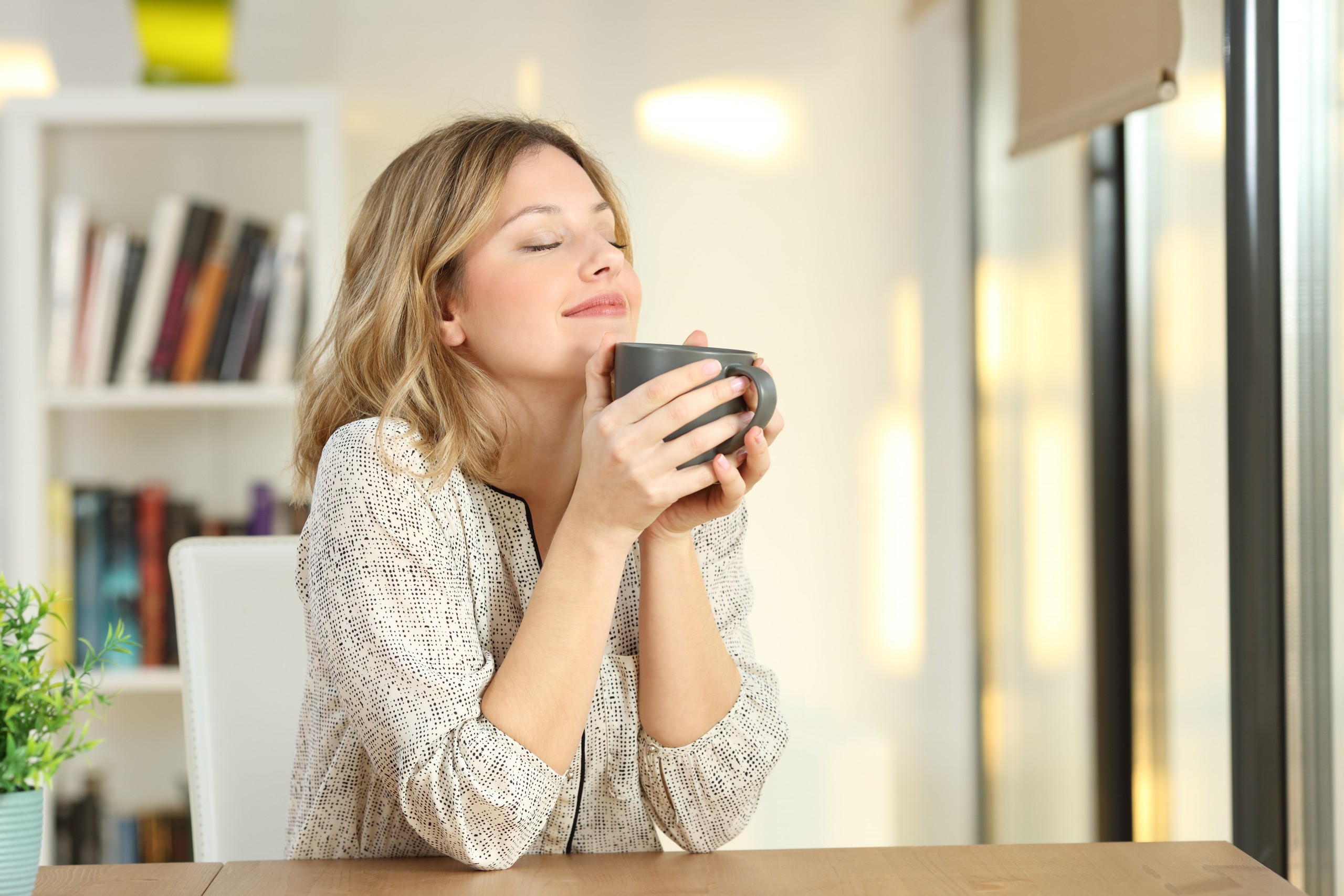 <p>Portrait of a woman breathing and holding a coffee mug at home</p>
