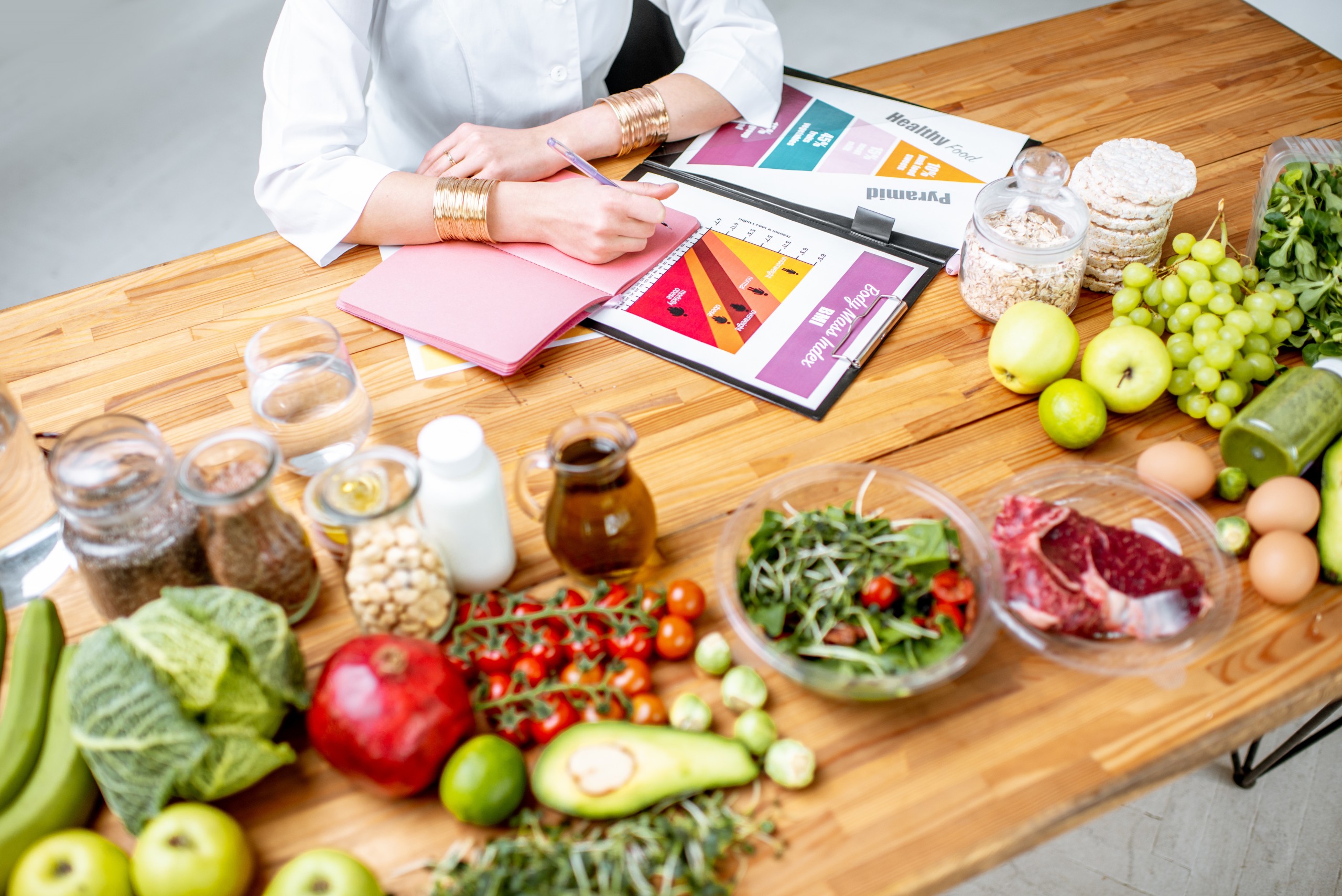 <p>Dietitian writing diet plan, view from above on the table with different healthy products and drawings on the topic of healthy eating</p>
