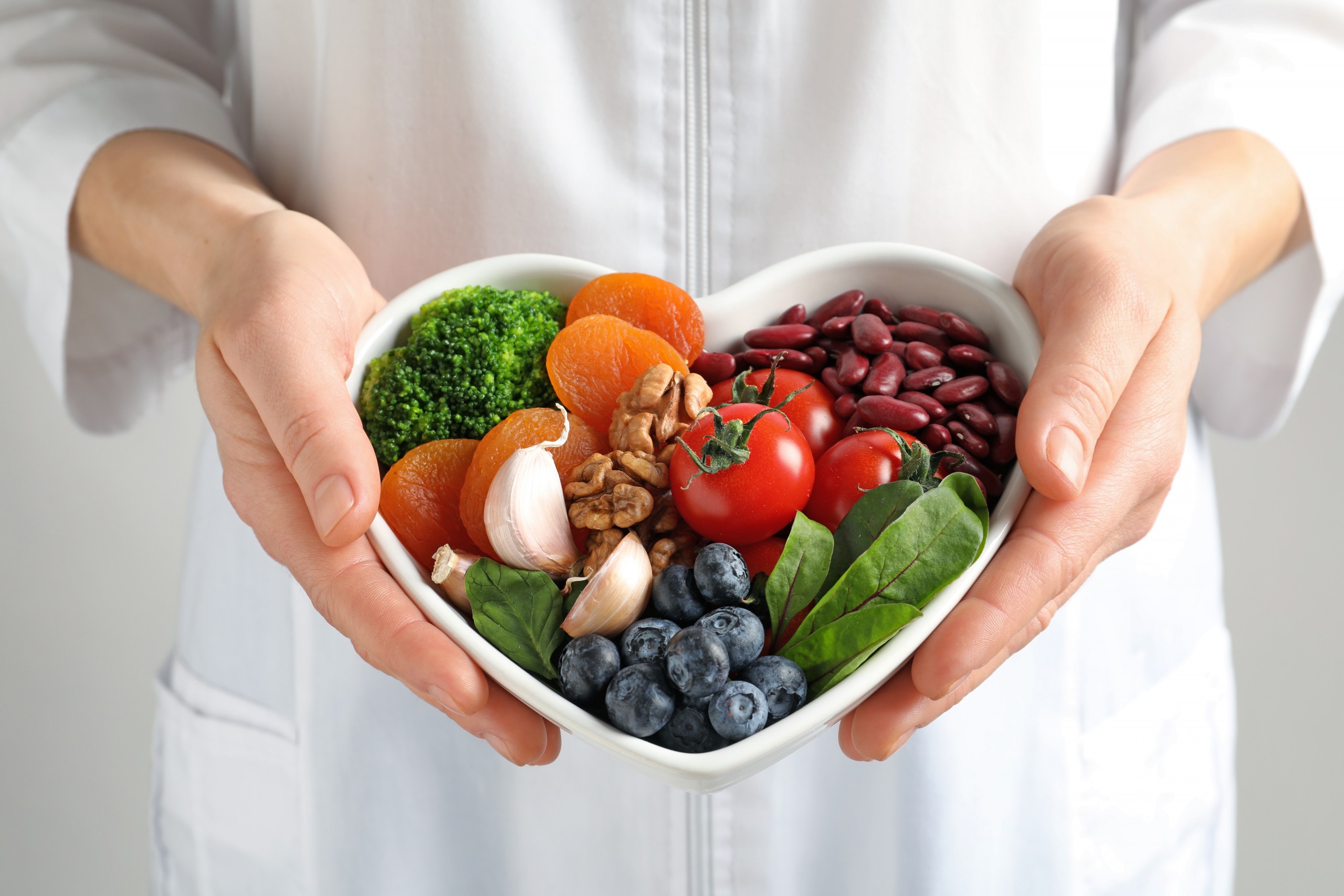 <p>Doctor holding bowl with products for heart-healthy diet, closeup</p>
