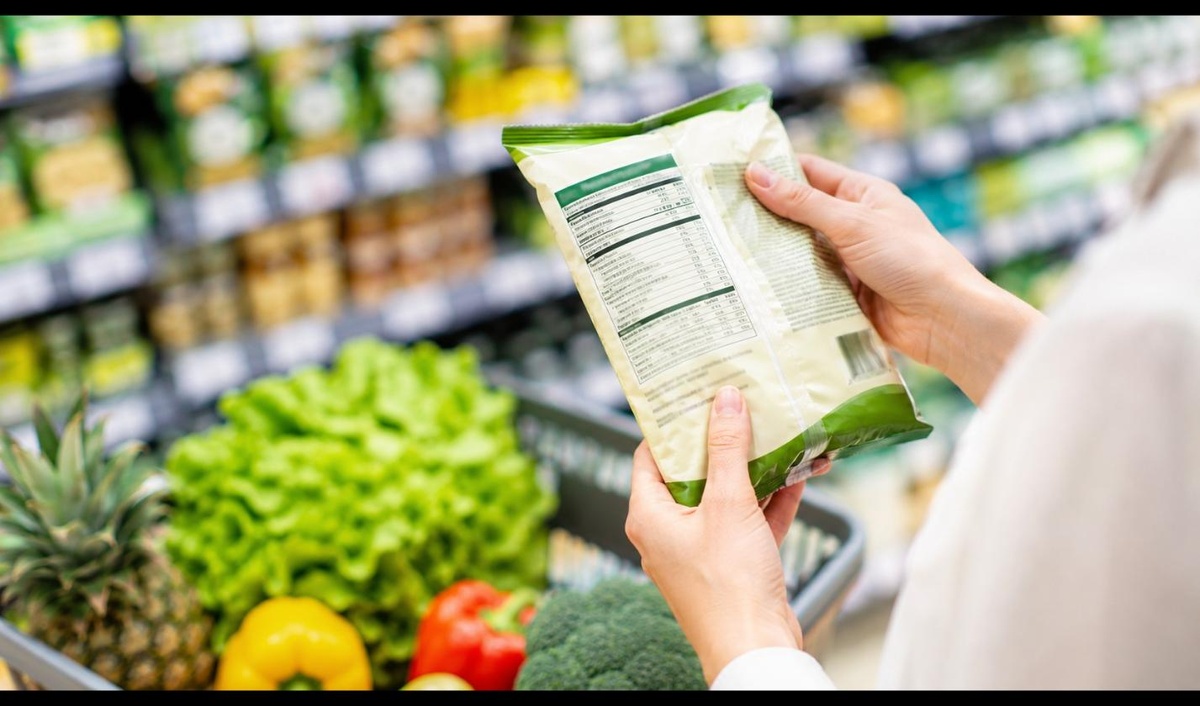 Kobieta w sklepie czyta etykietę i tabelę wartości odżywczych produktu spożywczego